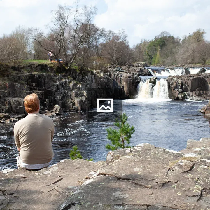Man on cliff with waterfall background