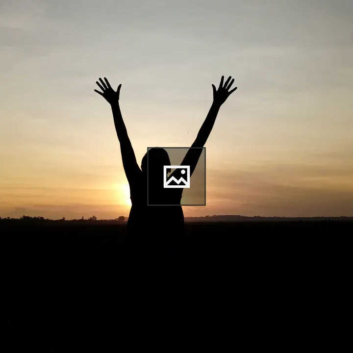 Person with arms raised at sunset
