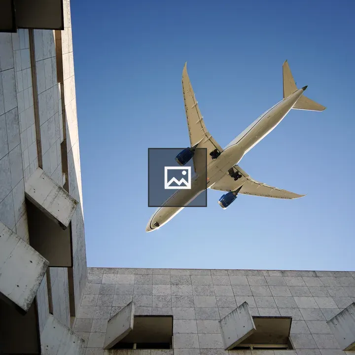 Airplane over blue sky between concrete walls