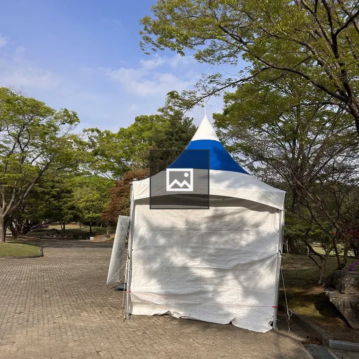 White tent with blue top in park