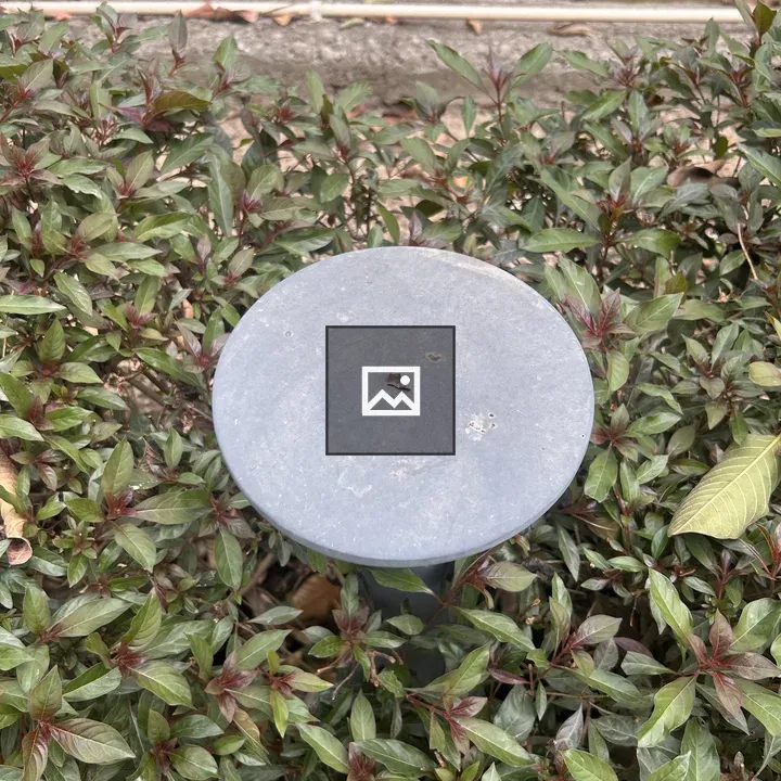 Round gray metal post among foliage