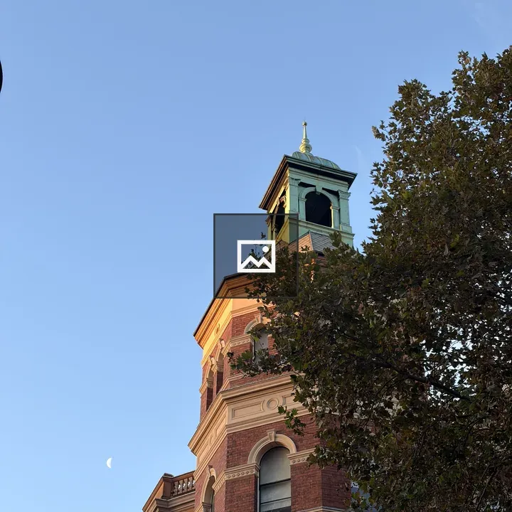 Historic brick building with green-topped tower