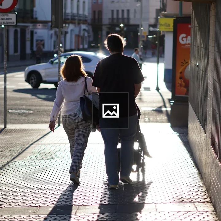 Couple Walking with Stroller on City Sidewalk