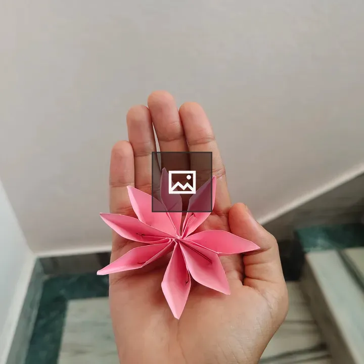 Hand holding pink origami flower