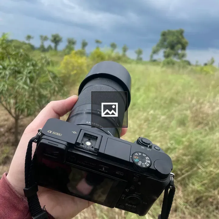 Person with Sony Alpha 6000 in Field