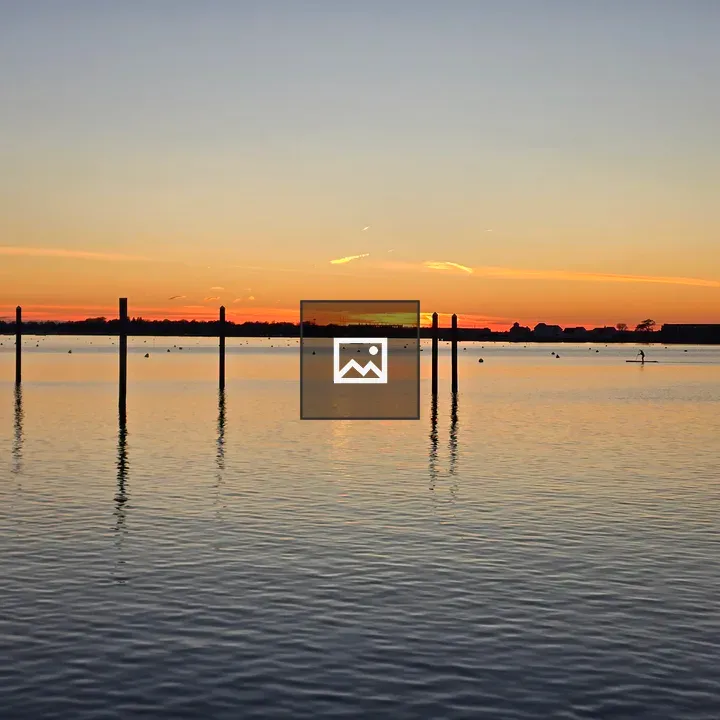 Sunset over calm waters with posts