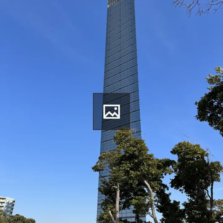 Tall glass skyscraper over trees