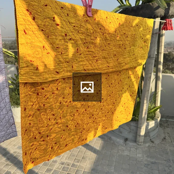 Yellow hand-stitched quilt on clothesline