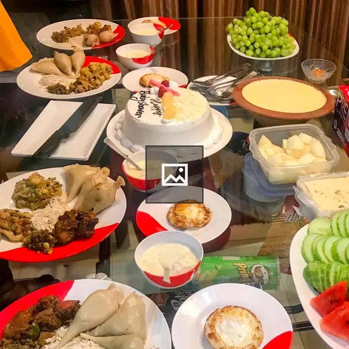 Birthday cake with assorted food on glass table