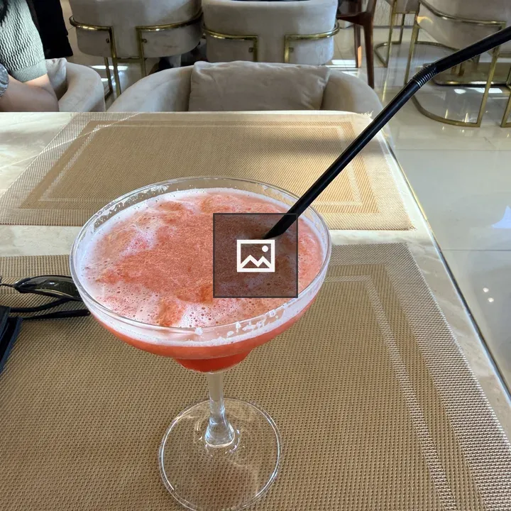 Pink cocktail in glass with straw