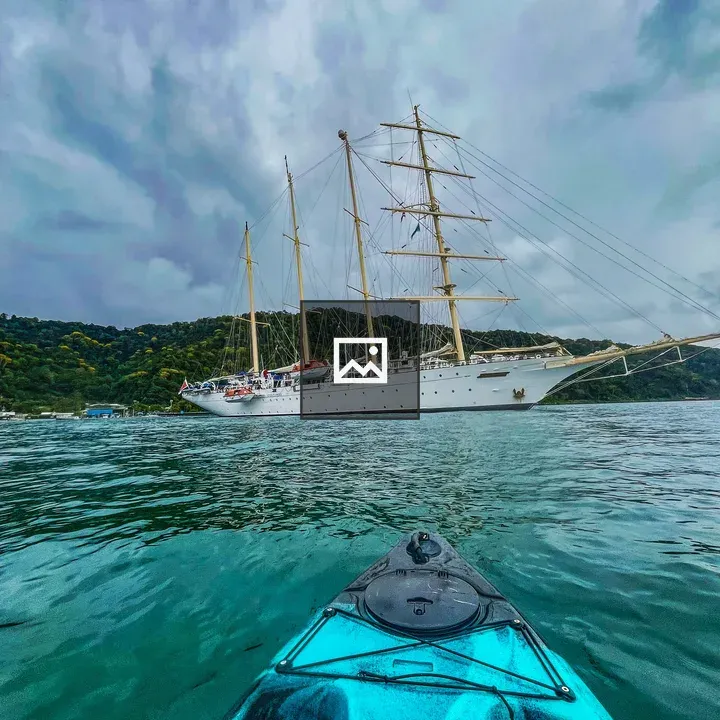 Kayak View of Sailboat on Green Sea