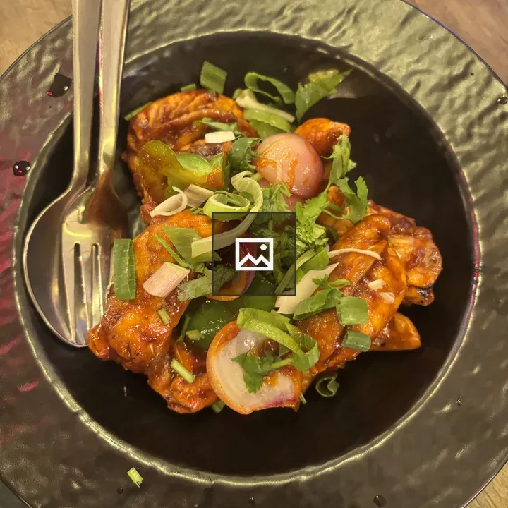 Chicken dish with greens on black plate