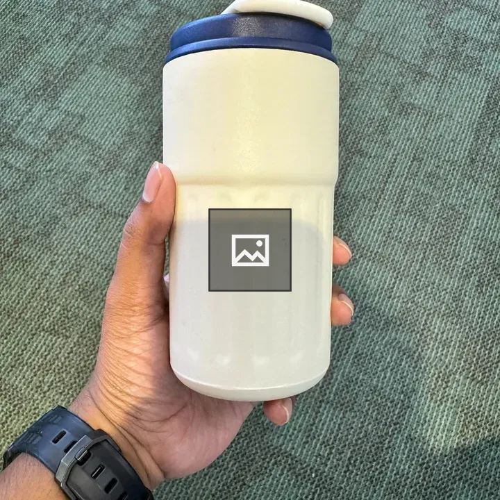 Hand holding white tumbler with blue lid