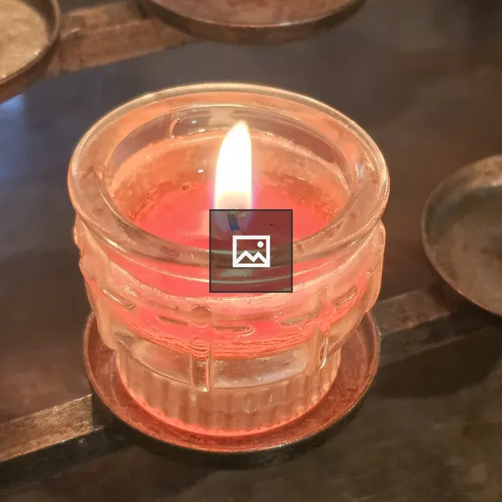 Lit red candle in glass holder