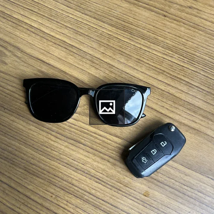 Sunglasses and car key on wood