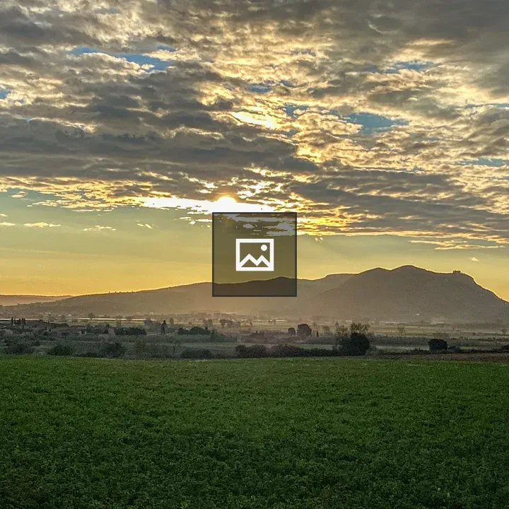 Scenic green field with mountain sunset