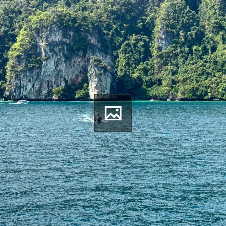 Tall limestone cliff by turquoise sea