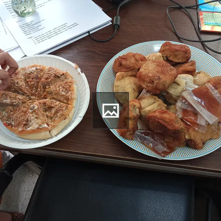 Pizza slice and snacks on desk