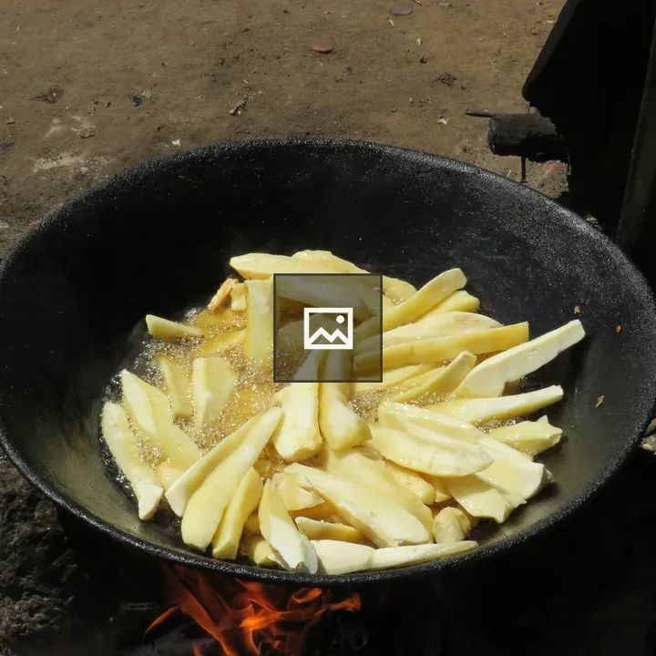 Sliced cassava frying in cast-iron wok