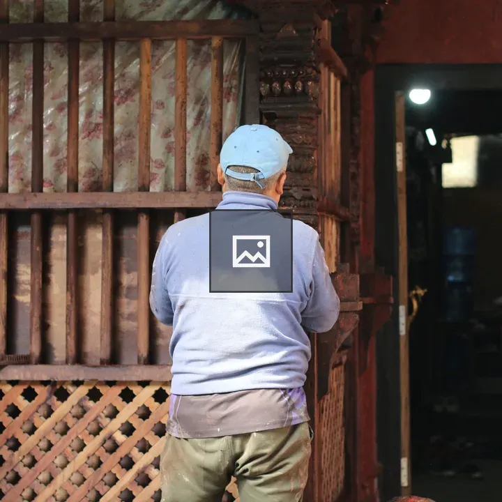 Man carving wood on traditional structure