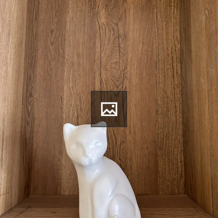 White ceramic cat figurine on shelf
