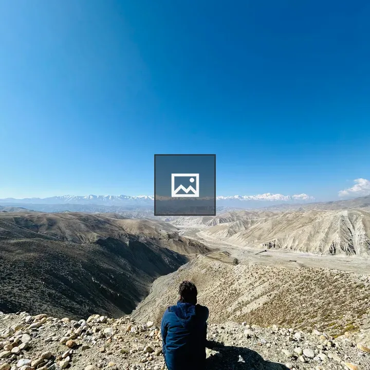Person on Rocky Ledge Overlooking Arid Landscape