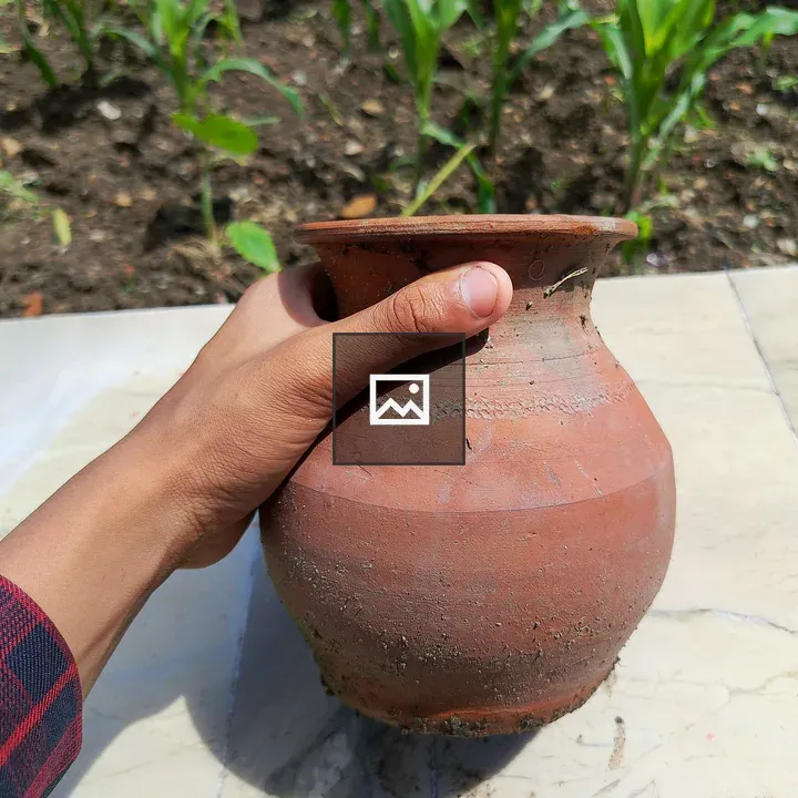 Hand holding clay pot outdoors