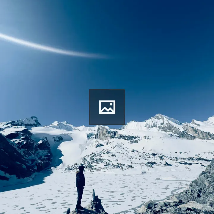 Person on rocky ledge with snowy mountains
