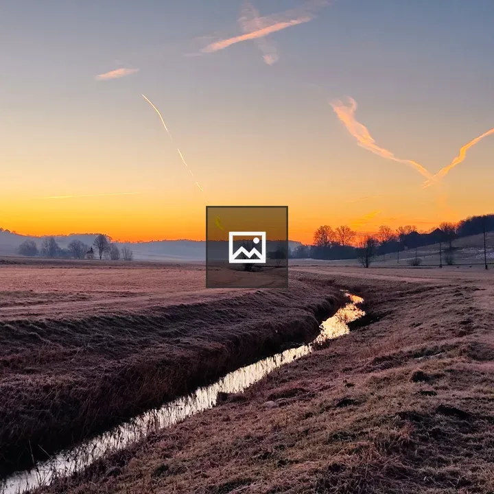 Sunrise over winter fields and stream