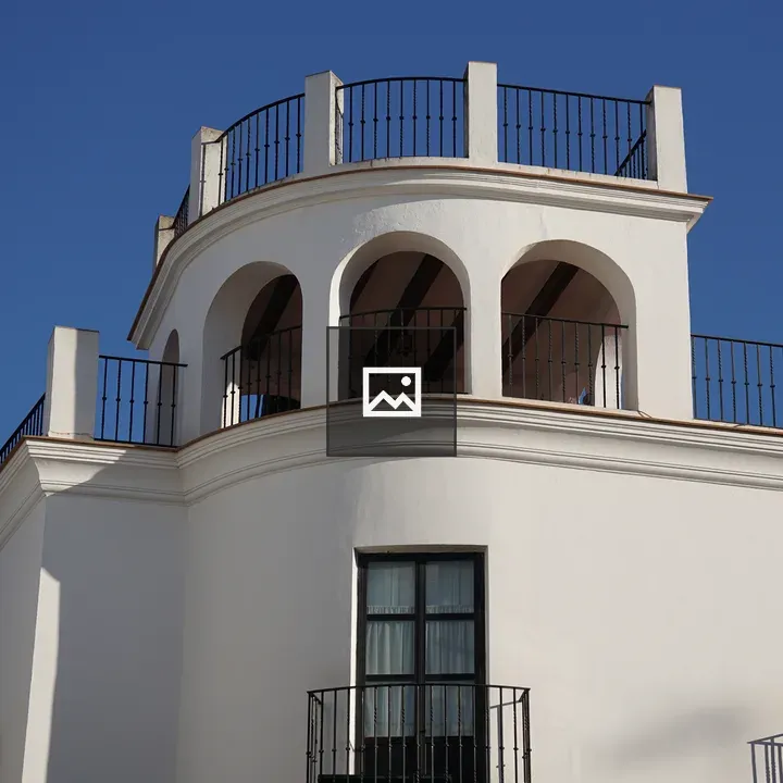 White building with rounded arches and balcony