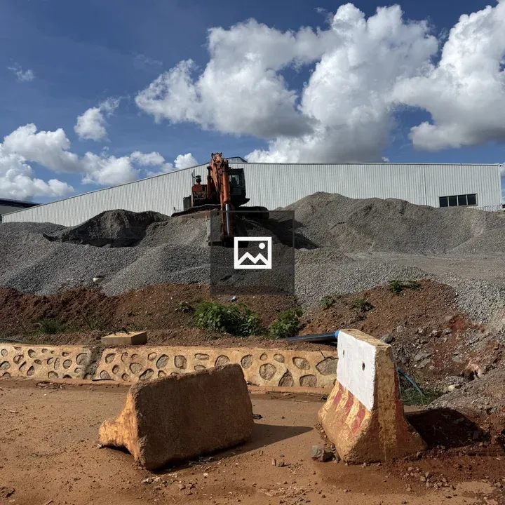 Digger at Gravel Mound Under Sky