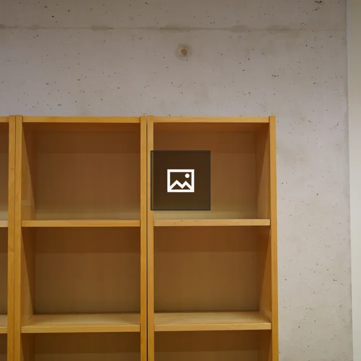 Wooden bookshelf against concrete wall