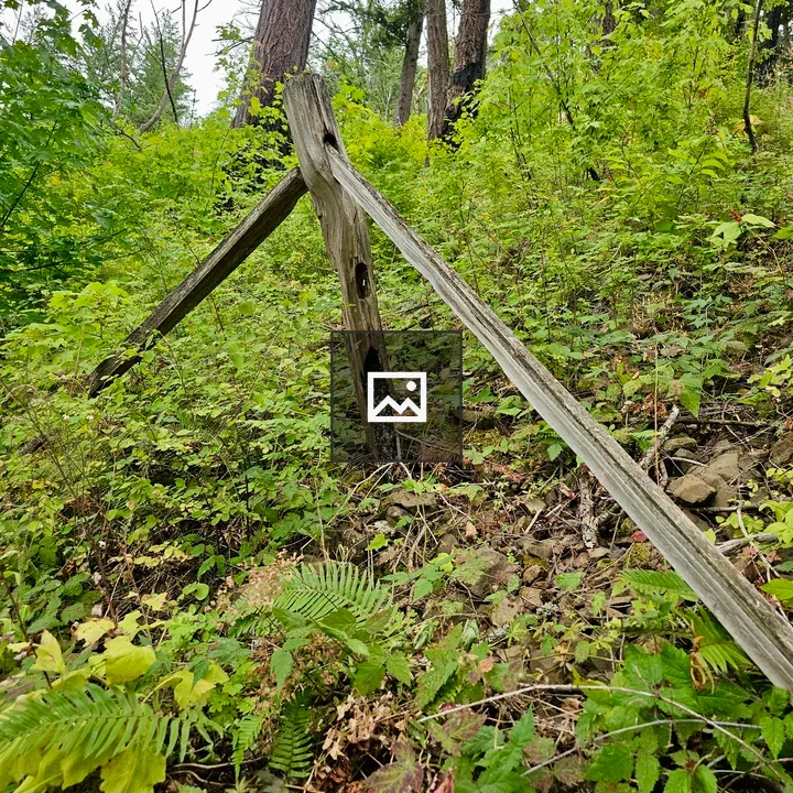 Tilted wooden fence against hillside