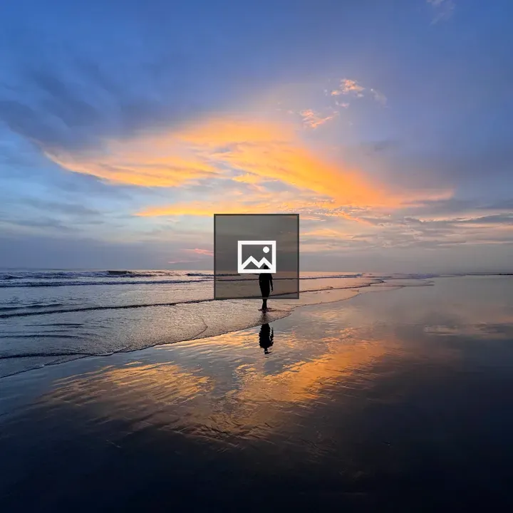 Person Walking on Wet Beach at Sunset